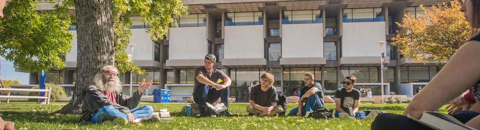 Students gathered under tree near Michener Library